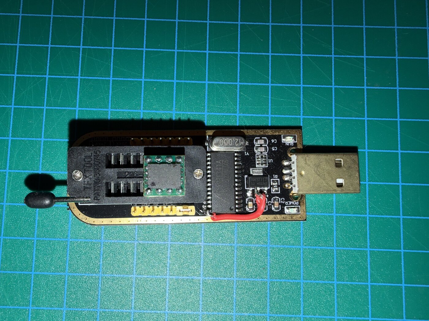 A black CH341A USB SPI programmer with a green SOIC socket in its ZIF connector
